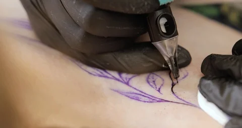 Closeup view of tattoo machine with needle is tattooing black leaves on skin. Stock Footage 113819839