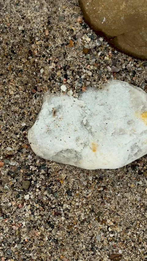 Closeup view of textured sandy beach surface with scattered pebbles and a s.. Stock-Footage 338414348