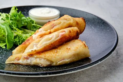 Closeup view of thin crepe stuffed with melted cheese and ham on a plate Foto stock