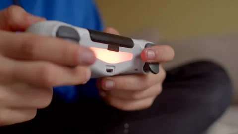 A closeup view of two hands gripping a PlayStation controller while immersed in  Stock Footage 295932136