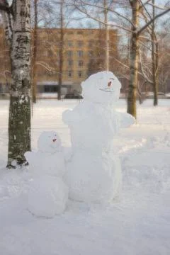 Closeup view of two snowmen big and small in a winter city park Stock Photos
