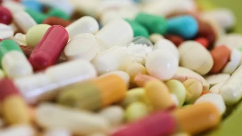 Closeup view of various pills spinning through view Stock Footage 95913223