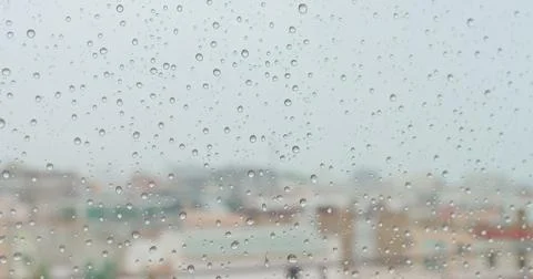Closeup view of water drops falling on glass. Rain running down on window. Rainy Stock Photos