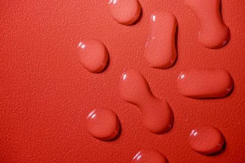 Closeup view of white fluid drops on a textured red background Stock Photos