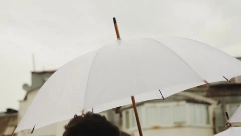 A closeup view of a white umbrella that is being held against an overcast Stock Footage 318064227
