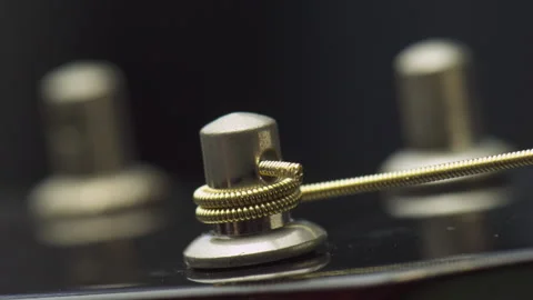 Closeup view of winding a new string onto guitar tuning peg Stock Footage 321527308