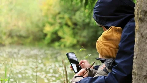 Closeup view of young father using smartphone with little son boy resting outsid 動画素材 215845107