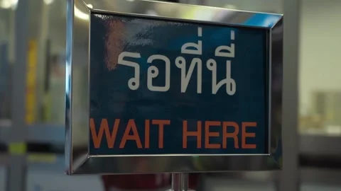 Closeup of wait here on the subway station before the cashier in thai and englis Stock Footage 299709674