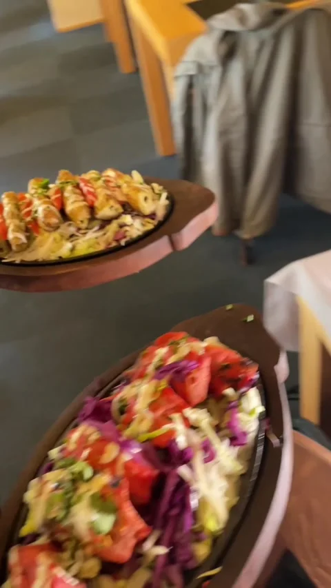 Closeup of waiter presenting vivid vegetable platter inside bustling cafe Stock Footage 335680417