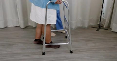 Closeup walker and legs of elderly male cancer survivor assisted by asian female Stock Footage 319055206