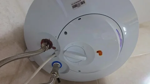Closeup of a wall-mounted water heater leaking from corroded pipe connections Stock Footage 337507477