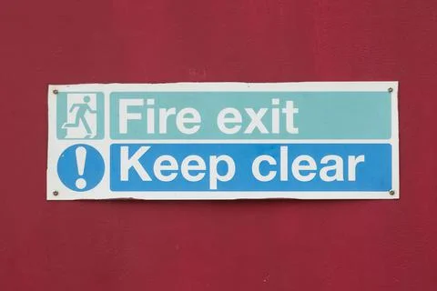 Closeup of a warning notice with the writing " Fire Exit, Keep Clear" on a red b Stock Photos