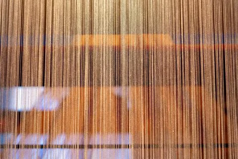 Closeup warp threads hanging on loom with reflected light and blur Stock Photos