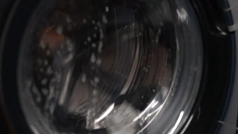 Closeup of washing machine drum rotating, cleaning clothes with water and Stock Footage 292695951