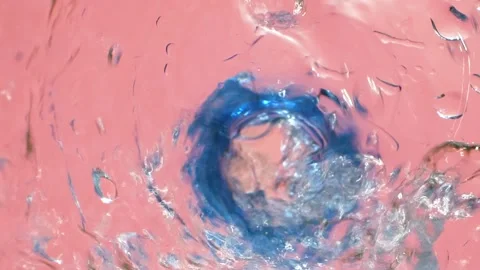 Closeup water falling down from bottle with drops splashing on pink, slow motion Stock Footage 155775323