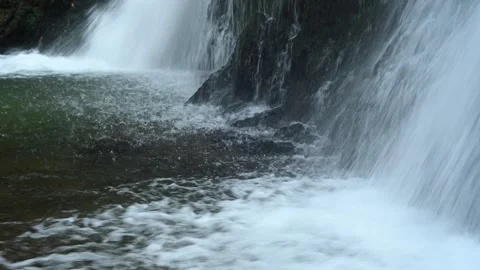 Closeup of water falling into the pond of a waterfall in autumn Video stock 288143044