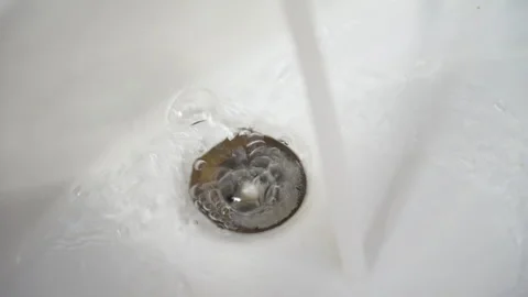 Closeup of water flowing down a bathroom sink drain 스톡 동영상 304230766