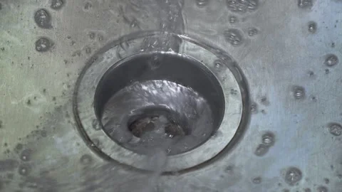Closeup of water going down the drain of a dirty, metal kitchen sink Vídeos de archivo 314244262