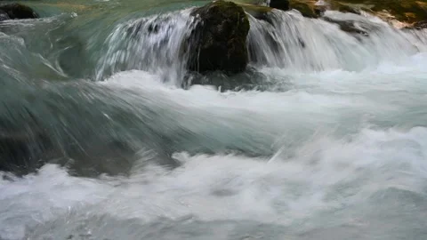 Closeup of water running over rocks of a mountain river  Video stock 260867405