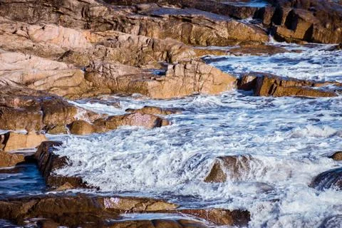 Closeup of a wave gently breaking over shallow rocks on the coast Foto stock