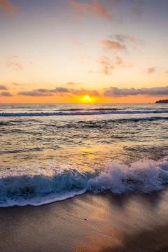Closeup of wave rolling on sandy shore at golden sunrise Stock Photos