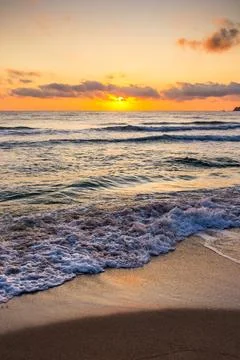 Closeup of wave rolling on sandy shore at golden sunrise Stock Photos