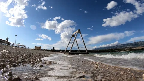 Closeup of waves crashing onto a beach with a swing in the background Stock Footage 150444295