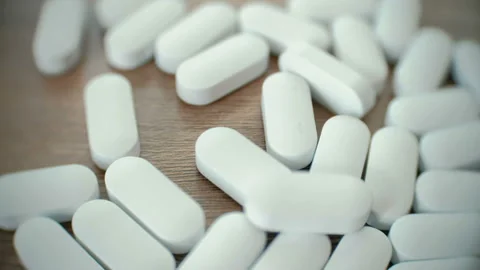 Closeup white oval pills fall on the table. Stock Footage 88558548