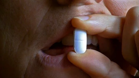 Closeup of a white pill placed in front of the mouth of a girl Stock-Footage 107482700