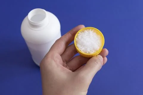 Closeup White Plastic Bottle, Cap Filled With Pipe Cleaner Granules In Hand Stock Photos