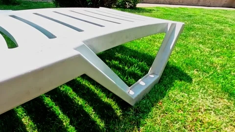 Closeup white plastic deckchair on the lawn Stock Footage 311234003