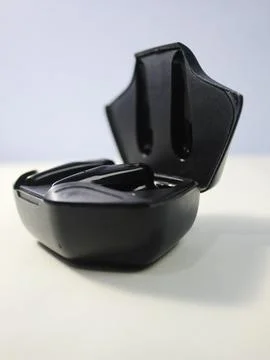 Closeup white true wireless stereo earbuds in case isolated on black background. Stock Photos