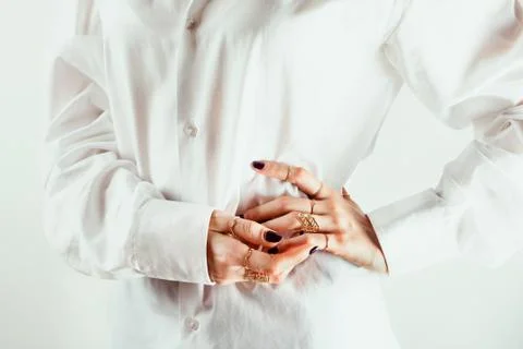 Closeup of white woman's hands with various rings around her waits, white shi Stock Photos