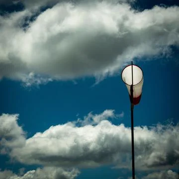 Closeup of a windsock indicator under the blue sky with clouds Stock Photos