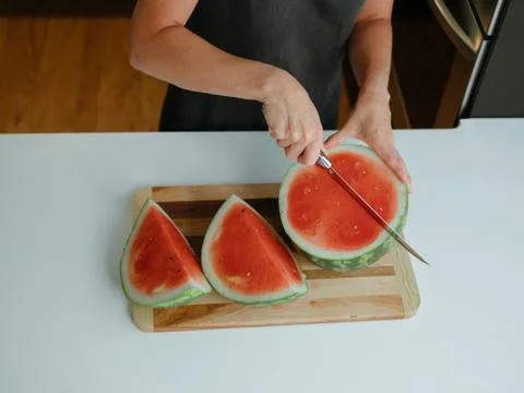 Closeup of woman cutting watermelon in cool, modern kitchen Stock Photos