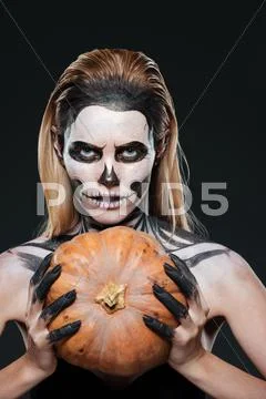 Closeup of woman with gothic skeleton makeup holding pumpkin Stock Photos