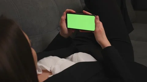 Closeup of woman lying on a Couch using Smartphone with Green Mock-up Screen Stock Footage 150167112