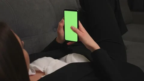 Closeup of woman lying on a Couch using Smartphone with Green Mock-up Screen Stock Footage 150167657