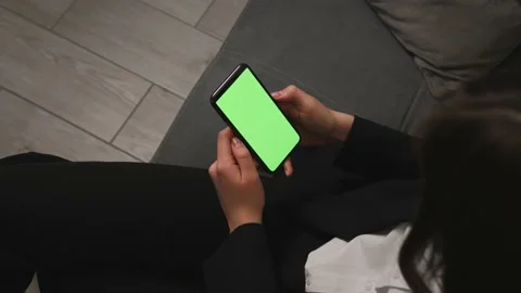Closeup of woman sitting on a Couch using Smartphone with Green Mock-up Screen Stock Footage 150167275