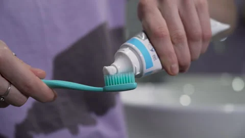 Closeup woman squeezing toothpaste onto a toothbrush in the bathroom at home 動画素材 268458853