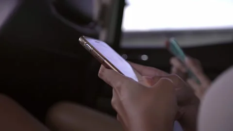 Closeup of a woman using a smartphone while seated in a car. A person with phone Stock Footage 299081816
