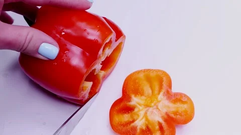 Closeup of a woman's hand cutting a red bell pepper on a white cutting board Video stock 168729235