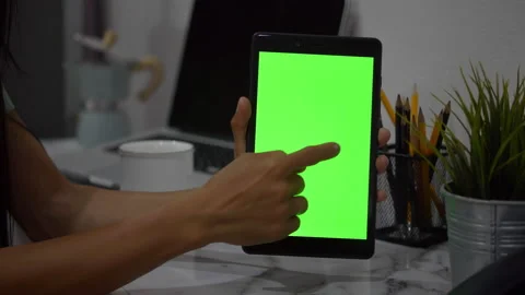 Closeup of a woman's hand holding a tablet with a vertical green screen.	 Stock Footage 133147625