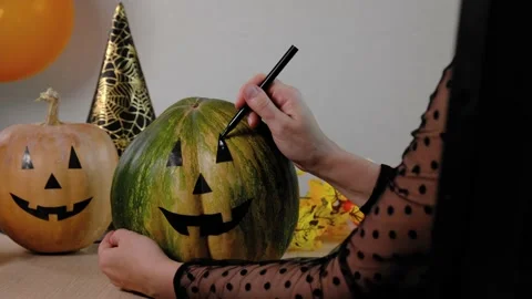 Closeup of woman's hand paint Pumpkins for Halloween while sitting at the table Stock Footage 161304499