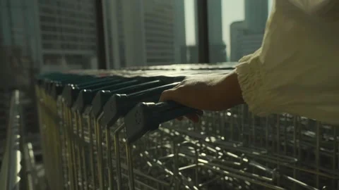 Closeup of woman's hand pulling out a shopping cast from a shopping cart row Video stock 299628926