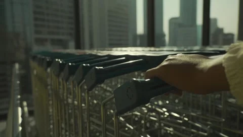 Closeup of woman's hand pulling out a shopping cast from a shopping cart row Video stock 299628928