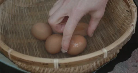Closeup of a woman's hand as she selects an egg from a basket and puts it in bag 库存影片 108628157