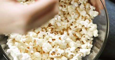 Closeup woman's hand taking popcorn from transparent bowl, top view. Stock Footage 127707510
