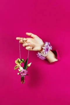 Closeup of woman's hand through torn paper holding bottle with bouquet on a s Stock Photos