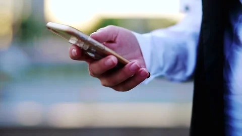 Closeup of woman's hands browsing mobilephone with a cityscape at the background 動画素材 76696041